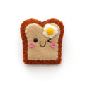 A cute, handcrafted felt pin shaped like a winking toast with a fried egg on top, set against a plain white background.