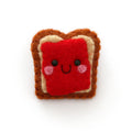 A cute felt pin shaped like a slice of toast with red jam and a smiling face, set against a plain white background.