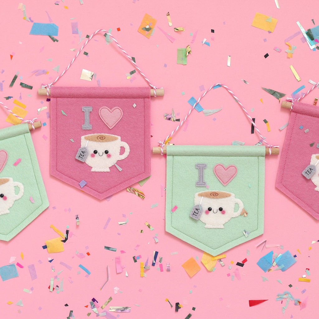 Felt Tea Banners featuring a Kawaii teacup with a happy face. The teacups have "I" and a heart above them. In this image the pink and mint style tea banners can be seen.