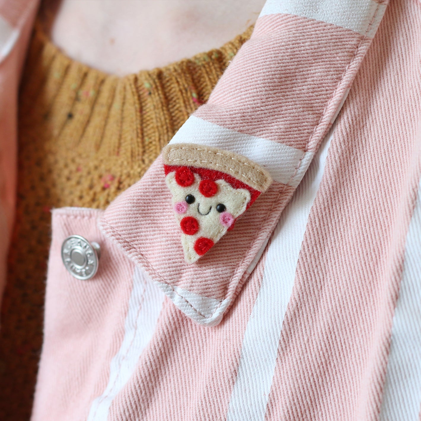 Pepperoni pizza felt brooch modelled on a pink and white striped denim jacket