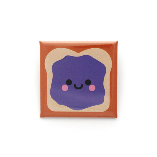 A 38mm square sandwich badge with a smear of purple jelly and a smiley face