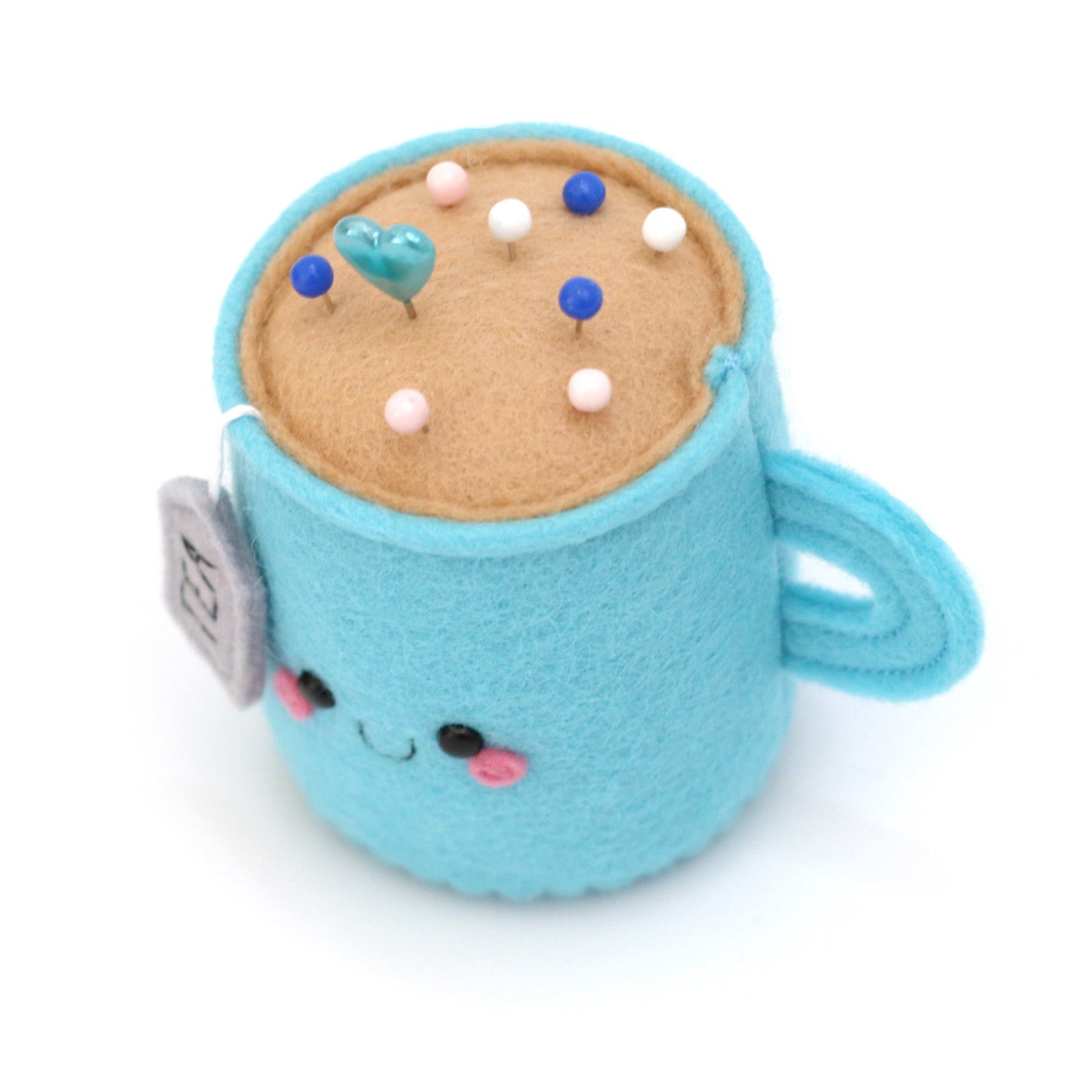 Pincushion shaped like a teacup holding various sewing pins
