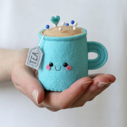 Hand holding blue pincushion made from felt in the shape of a tea mug